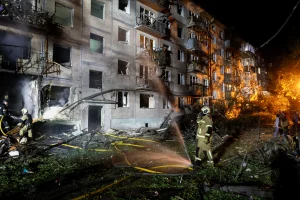 Пожежники гасять пожежу біля зруйнованого багатоповерхівки вночі серед уламків